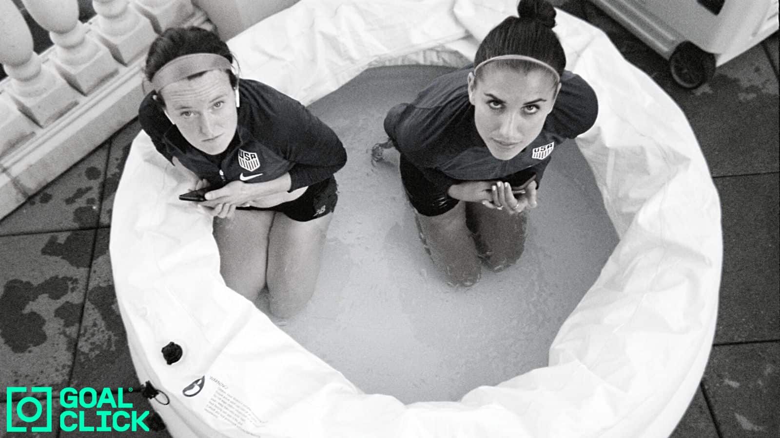 A photo from a Goal Click series at the 2019 Women's World Cup of Alex Morgan and Rose Lavelle sitting in their uniforms in a blow up pool with water.